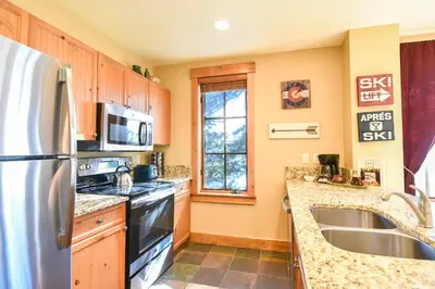 a kitchen with a stainless steel refrigerator and a sink at The Springs at River Run - Walk to Lifts, Pool Hot Tubs in Keystone