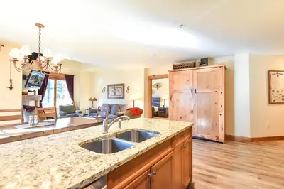 a kitchen with a sink and a living room at The Springs at River Run - Walk to Lifts, Pool Hot Tubs in Keystone