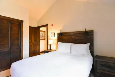 a bedroom with a white bed with a wooden headboard at Red Hawk Townhome - Walk to Lifts, Pool/Hot Tub Access in Keystone