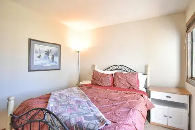a bedroom with a bed with a pink comforter at Centennial Townhome - Mountain/Lake Views Pool Access in Dillon
