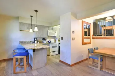 a kitchen with white cabinets and a wooden table at Centennial Townhome - Mountain/Lake Views Pool Access in Dillon