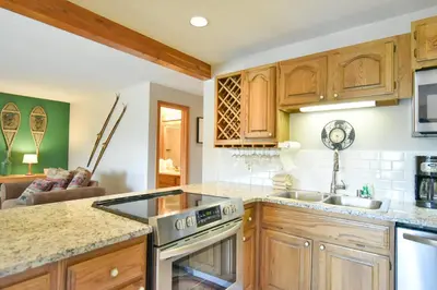 a kitchen with wooden cabinets and a stove top oven at Timber Ridge Retreat - Pool, Hot Tub, Sauna + More in Silverthorne