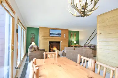 a living room with a table and a fireplace at Timber Ridge Retreat - Pool, Hot Tub, Sauna + More in Silverthorne