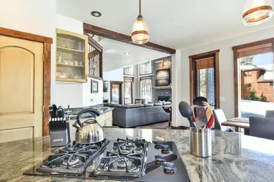 a kitchen with a stove top oven next to a living room at Shekel Haus – Luxury Mountain Retreat w/ Views Hot Tub in Breckenridge