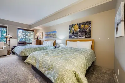 a bedroom with two beds and a chair and windows at 2747 Slopeside studio in Keystone