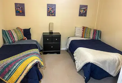 a room with two beds and a night stand in it at Private Basement Suite Bedrooms Bath Kitchen office Theater in Broomfield