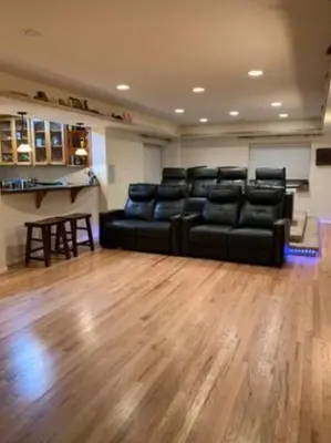 a living room with a black couch and a wooden floor at Private Basement Suite Bedrooms Bath Kitchen office Theater in Broomfield