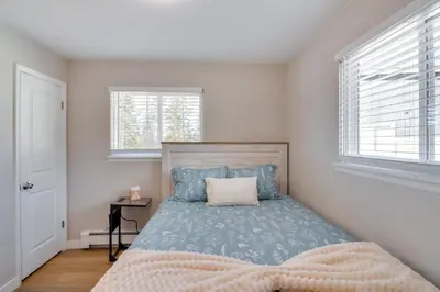 a bedroom with a bed and two windows at 3BR Riverfront Retreat! Mtn Views, Community Perks in Winter Park