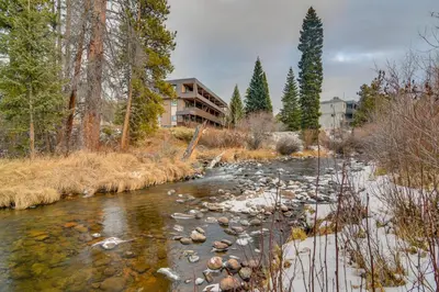 a river with rocks and trees and a building at 3BR Riverfront Retreat! Mtn Views, Community Perks in Winter Park