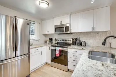 a kitchen with white cabinets and a stainless steel refrigerator at Hot Tub Access Condo 2 Mi to Winter Park Resort! in Winter Park