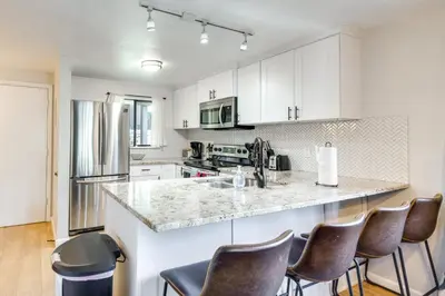 a kitchen with white cabinets and a counter with chairs at Hot Tub Access Condo 2 Mi to Winter Park Resort! in Winter Park