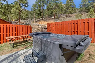 a hot tub sitting next to a bench and a fence at Cabin 1- Hot Tub Grill- Mins to RMNP in Estes Park