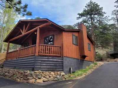 a log cabin with a deck on the side of a road at Cabin 1- Hot Tub Grill- Mins to RMNP in Estes Park