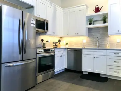 a kitchen with white cabinets and a stainless steel refrigerator at Steps to Lake Fireplace Indoor Outdoor Oasis in Grand Lake