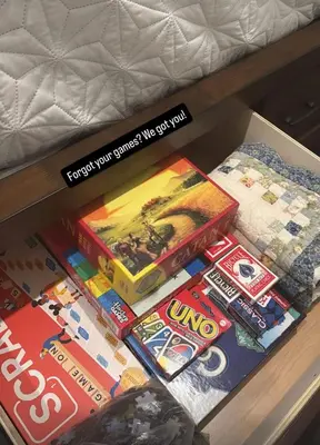 a box of games on a table next to a bed at Steps to Lake Fireplace Indoor Outdoor Oasis in Grand Lake