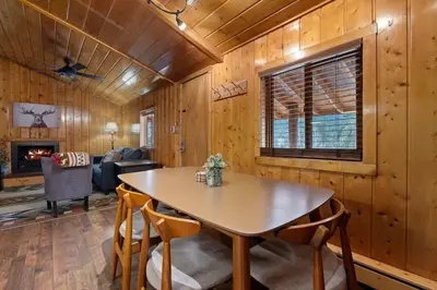a dining room with a table and a living room at Cabin 2- Two BR Cabin w Hot Tub in Estes Park