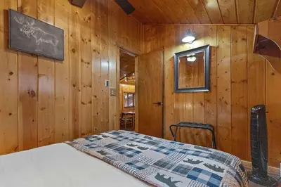 a bedroom with wooden walls and a bed in a room at Cabin 2- Two BR Cabin w Hot Tub in Estes Park