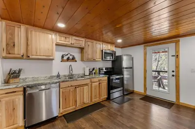 a kitchen with wooden cabinets and stainless steel appliances at Cabin 3- Cozy updated cabin 5 min to RMNP in Estes Park