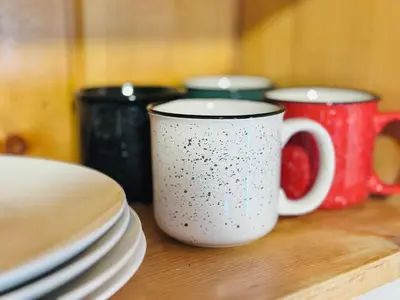 two coffee mugs sitting on a wooden table with plates at Cabin 4- One Bedroom cabin- RMNP in Estes Park
