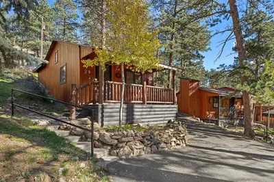 a cabin in the woods with a porch and stairs to it at Cabin 5- Private Cabin w King bed kitchen porch in Estes Park