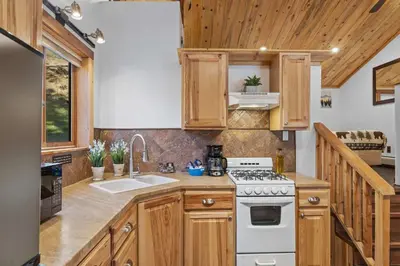 a kitchen with wooden cabinets and a white stove top oven at Cabin 5- Private Cabin w King bed kitchen porch in Estes Park