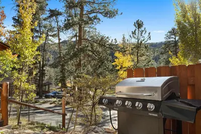 a grill sitting in a yard next to a fence at Cabin 6- Private Hot Tub 5 Min to RMNP in Estes Park