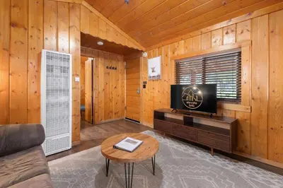 a living room with a tv and a couch and a table at Cabin 6- Private Hot Tub 5 Min to RMNP in Estes Park