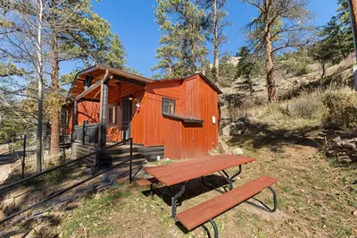 a wooden cabin with a picnic table and a bench at Cabin 7- Studio Cabin Heated Floors 5 Min to RMNP in Estes Park