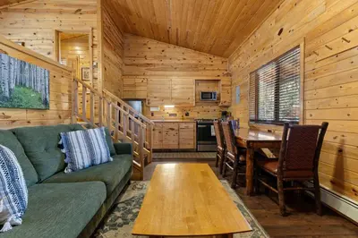 a living room with a couch and a table in a cabin at Cabin 8-Cozy King Loft Cabin 5 Min to RMNP in Estes Park