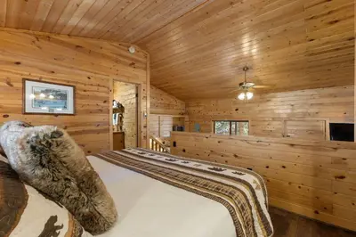 a bedroom with a bed in a wooden cabin at Cabin 8-Cozy King Loft Cabin 5 Min to RMNP in Estes Park
