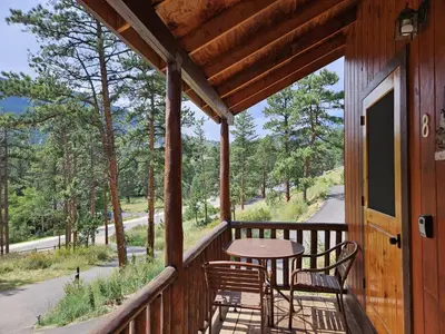 a balcony with a table and chairs on a cabin at Cabin 8-Cozy King Loft Cabin 5 Min to RMNP in Estes Park