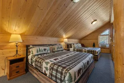 a bedroom with two beds in a log cabin at Cabin 9- Spacious cabin- 4 King beds- 2 baths in Estes Park
