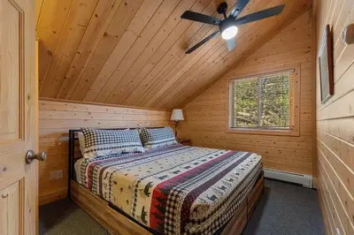 a bedroom with a bed in a wooden cabin at Cabin 9- Spacious cabin- 4 King beds- 2 baths in Estes Park