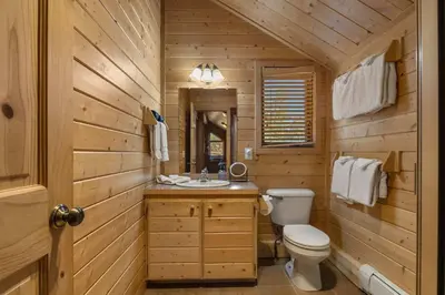 a wooden bathroom with a toilet and a sink at Cabin 9- Spacious cabin- 4 King beds- 2 baths in Estes Park