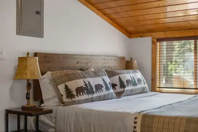 a bed in a bedroom with a wooden ceiling at Cabin 10- King Cabin Mins to RMNP in Estes Park