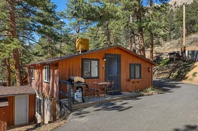 a small cabin with a table and a chair on the porch at Cabin 10- King Cabin Mins to RMNP in Estes Park