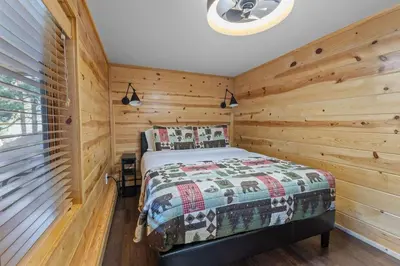 a bedroom with a bed in a wooden room at Cabin 12 - Spacious & Updated -Hot Tub & King Beds in Estes Park