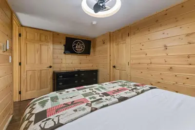 a bedroom with a bed and a wooden wall at Cabin 12 - Spacious & Updated -Hot Tub & King Beds in Estes Park