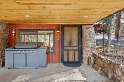 a grill outside of a house with a wooden roof at Cabin 12 - Spacious & Updated -Hot Tub & King Beds in Estes Park