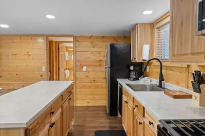 a kitchen with wooden cabinets and a black refrigerator at Cabin 12 - Spacious & Updated -Hot Tub & King Beds in Estes Park