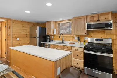 a kitchen with wooden cabinets and a stove top oven at Cabin 12 - Spacious & Updated -Hot Tub & King Beds in Estes Park