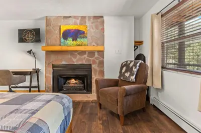 a bedroom with a fireplace and a chair and a bed at Cabin 14 - King Bed hotel-style unit in Estes Park