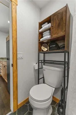 a bathroom with a toilet and a shelf with towels at Cabin15 - King bed Hotel Style Unit in Estes Park