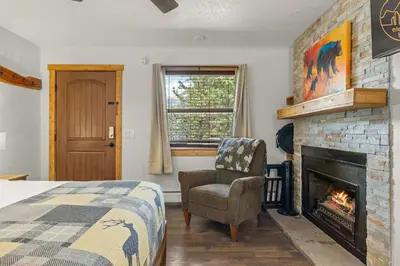 a bedroom with a fireplace and a bed and a chair at Cabin15 - King bed Hotel Style Unit in Estes Park