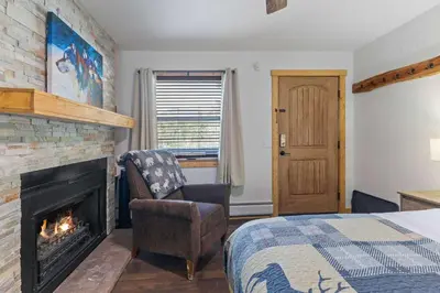 a bedroom with a fireplace and a bed and a chair at Cabin16 - King Bed Kitchenette & Bath in Estes Park