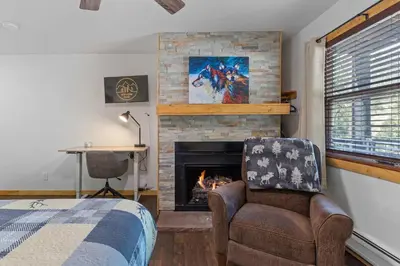 a bedroom with a fireplace and a bed and a chair at Cabin16 - King Bed Kitchenette & Bath in Estes Park