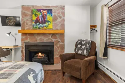 a bedroom with a fireplace and a chair and a bed at Cabin 17 - King Bed New Kitchen & Bath in Estes Park