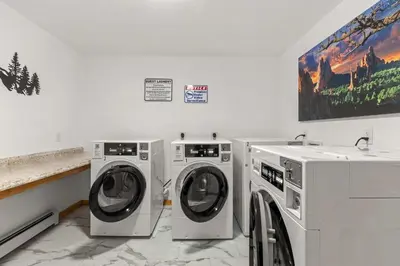 a laundry room with two washing machines and a painting at Cabin 18 - King Bed Mountain views Hotel Style in Estes Park