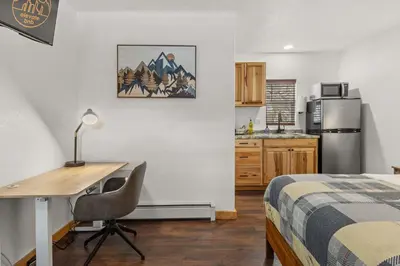 a bedroom with a desk and a bed and a kitchen at Cabin 18 - King Bed Mountain views Hotel Style in Estes Park