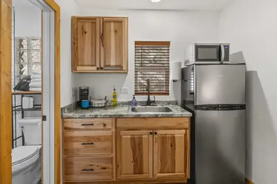 a small kitchen with a refrigerator and a sink at Cabin 18 - King Bed Mountain views Hotel Style in Estes Park
